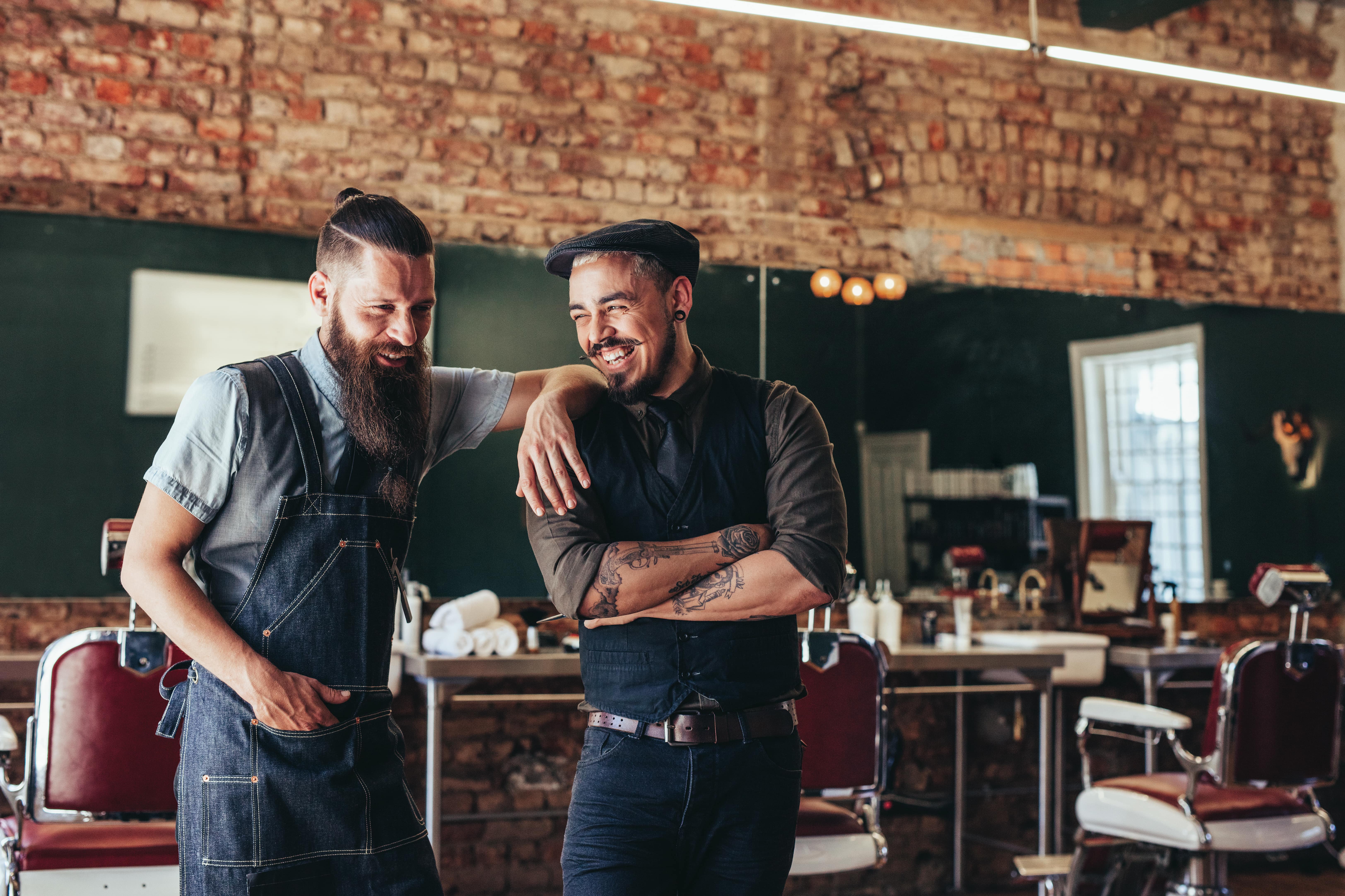 two barbers in a barber shop laughing 