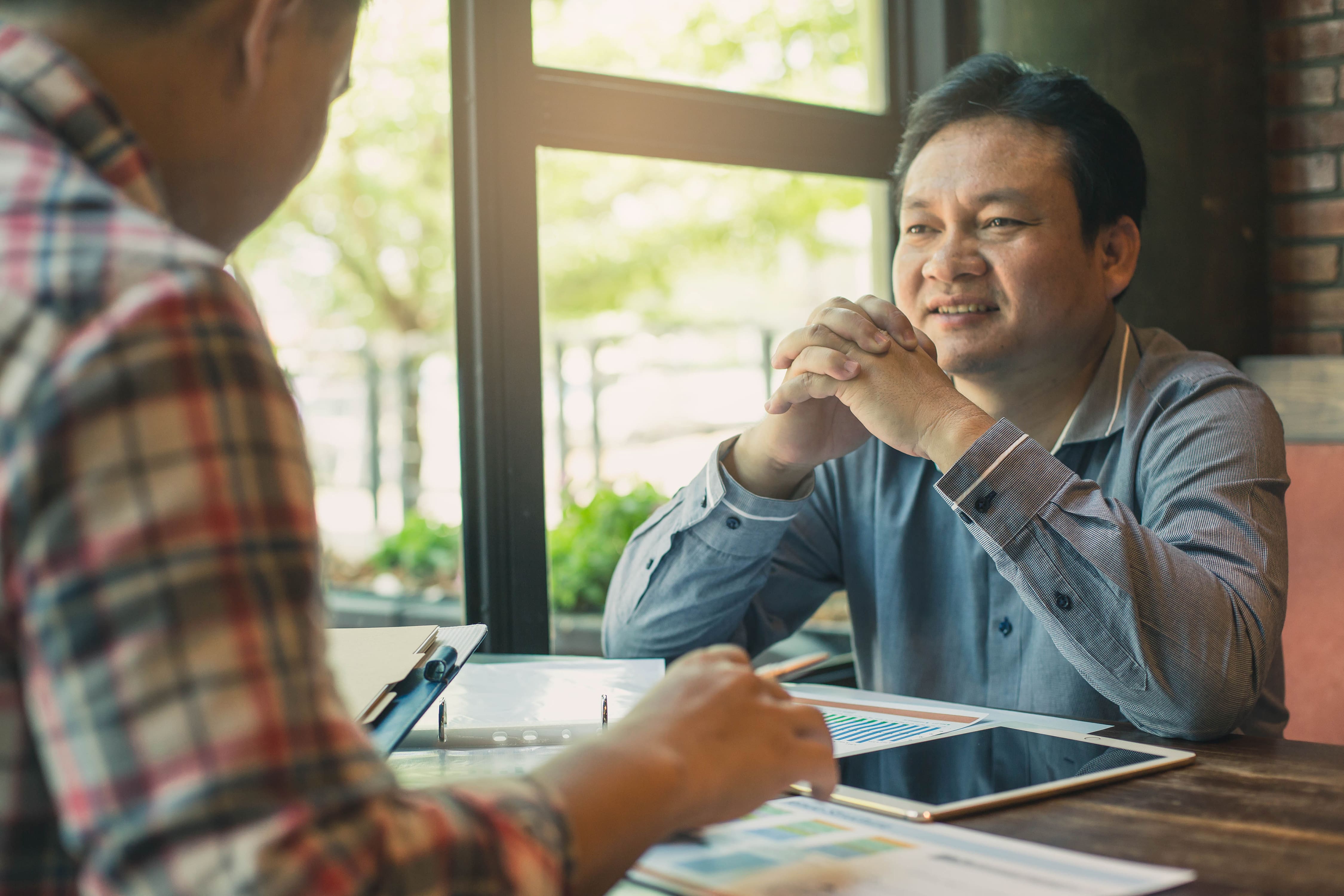 Business people negotiating a contract, they are pointing on a document and discussing together. Two businessmen are negotiating in office.